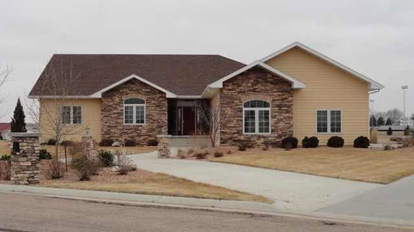 Beautiful house featuring brick and siding exterior, lush front lawn, and modern design.