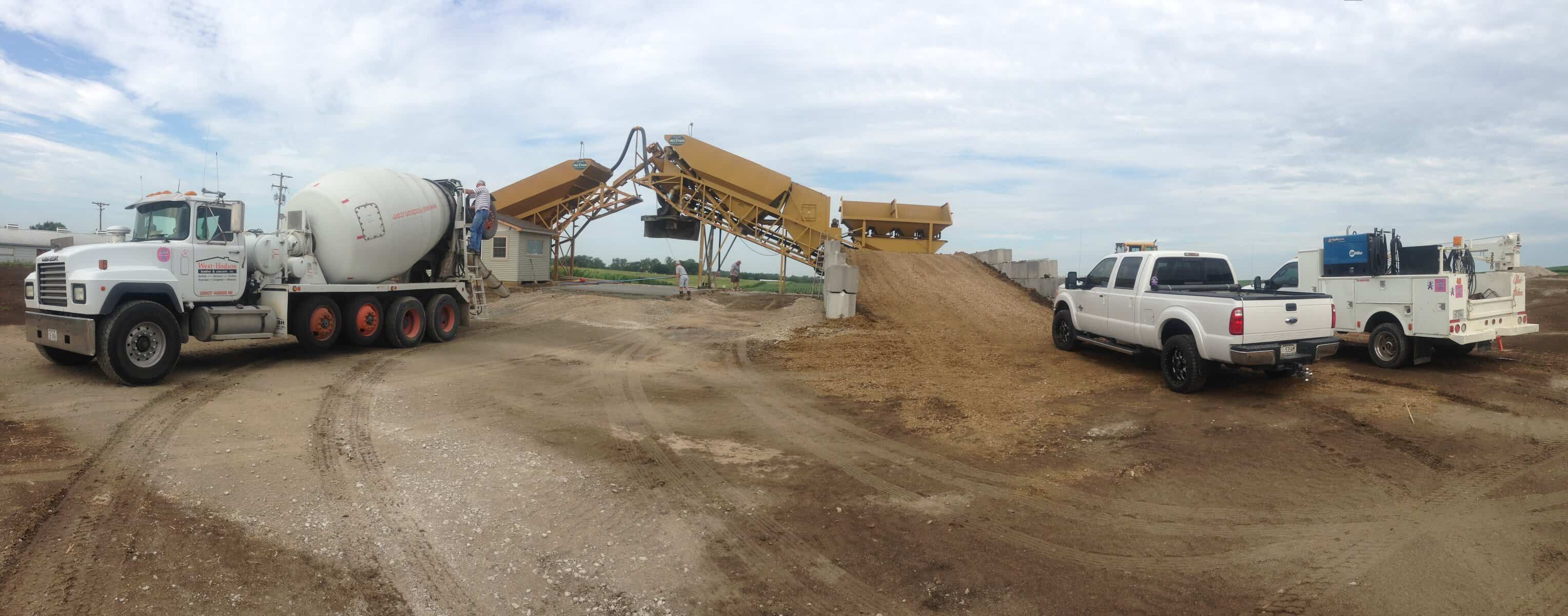The image depicts a concrete batching process with trucks and machinery on a construction site, highlighting professional concrete mixing services.