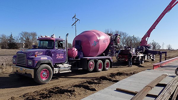 Heavy-duty concrete mixer truck on construction site with crane.