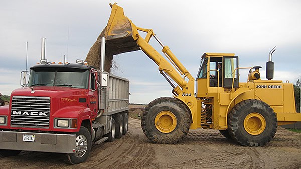 Construction machinery at work site with excavator loading truck.