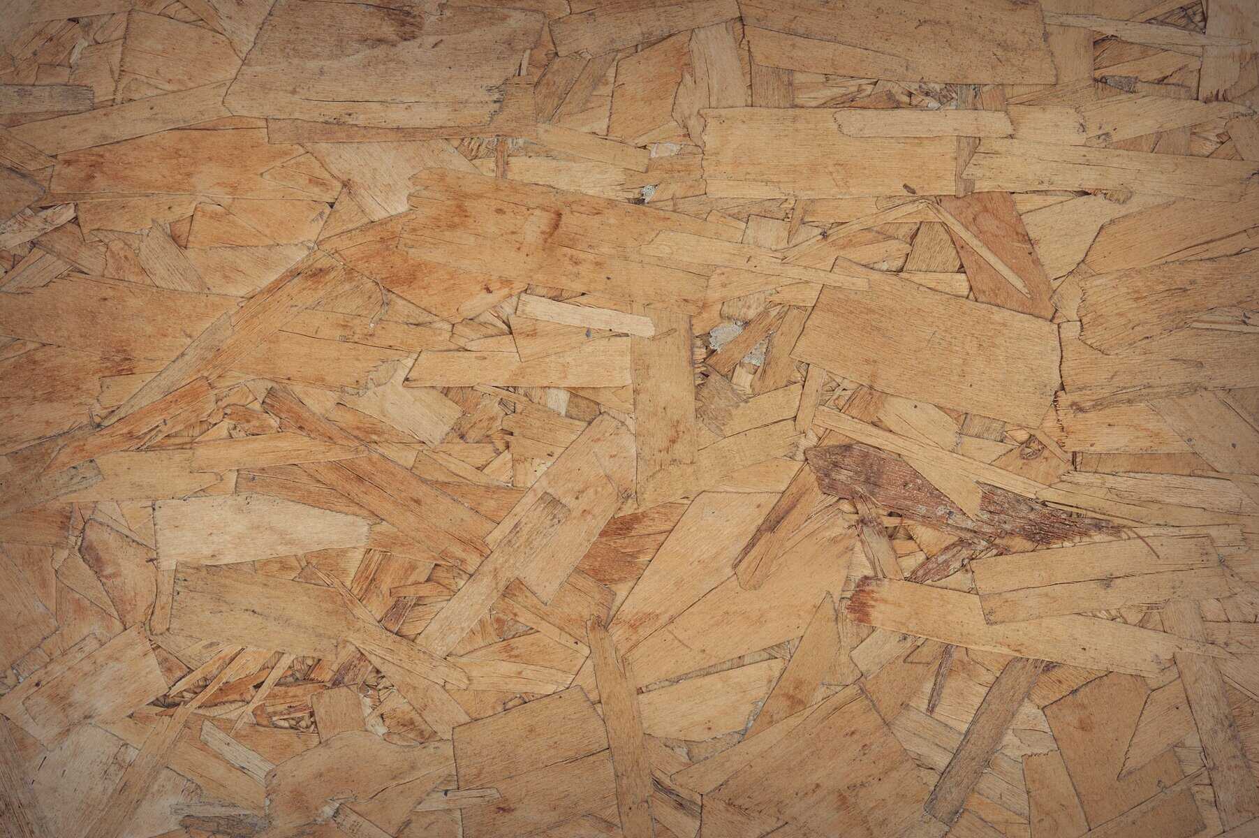 Close-up of OSB board showcasing layered wood chips and shavings for building projects.